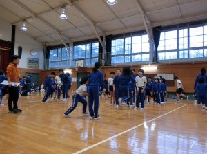 体育館で多くの児童が集まり、グループに分かれて縄跳びを行っている写真