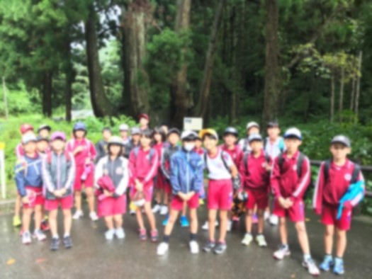 秋季遠足で森の前に児童が集まり記念撮影をしている写真