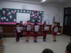 児童たちが前に並び、紙を掲げて発表している写真