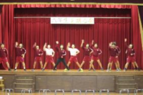 児童たちが舞台で振りを揃えて踊っている写真