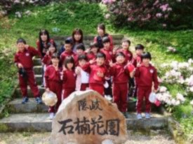 石楠花園の碑の後ろに児童たちが並んで記念撮影をしている写真