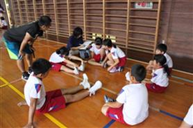 体育館で子どもたちが輪になって座りながら話している写真