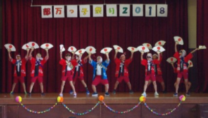 舞台で生徒たちが扇子を持ち踊っている写真