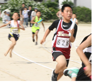 児童たちがグラウンドでリレーをして競っている様子