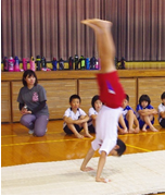 体育館のマットの上で児童が逆立ちを披露している写真