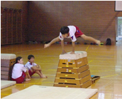 体育館で児童が跳び箱を飛んでいる写真