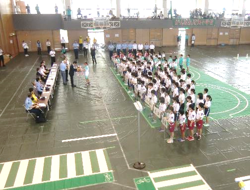 体育館にコースが設置され、椅子に座る警察署の方と向き合うように児童が整列している写真