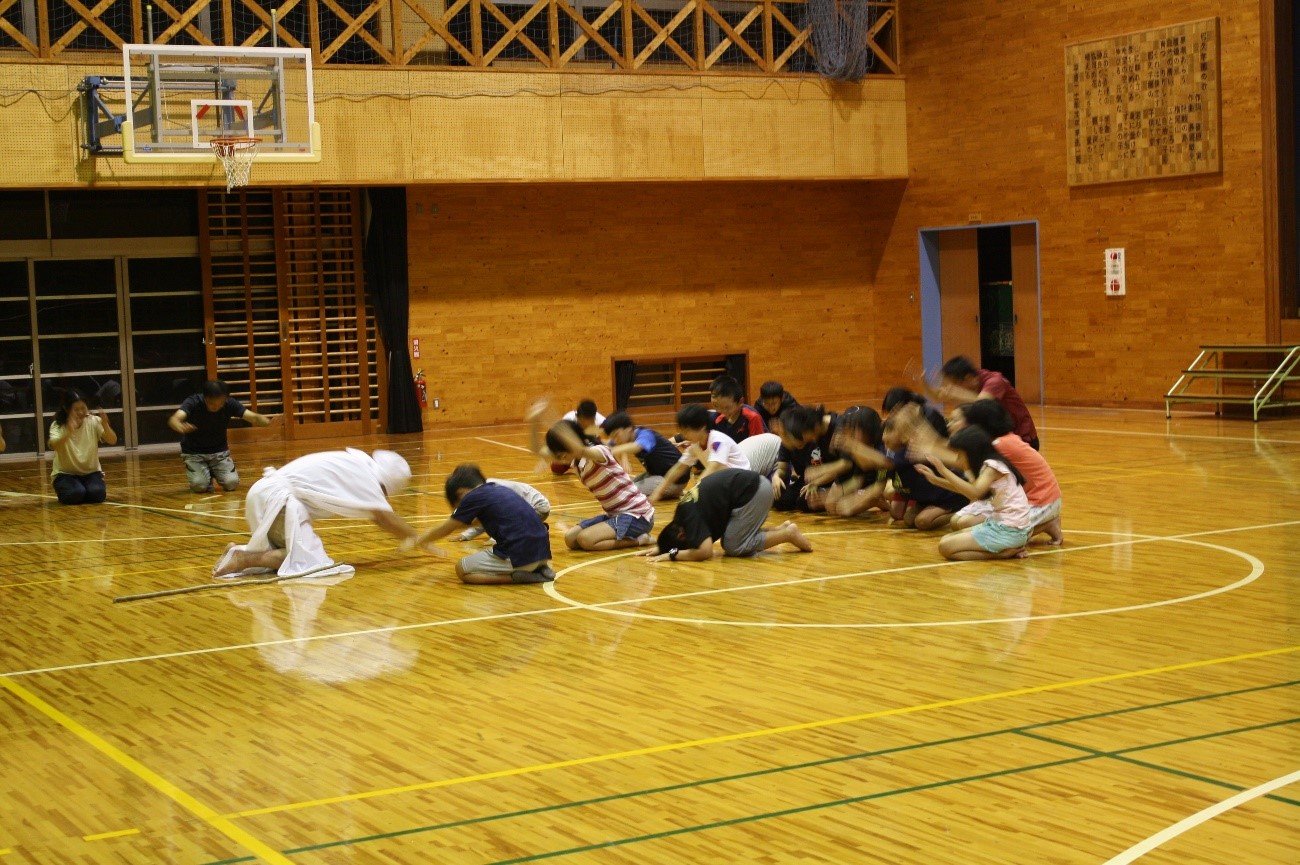 衣装を着た複数の児童が正座をし、演技をしている写真