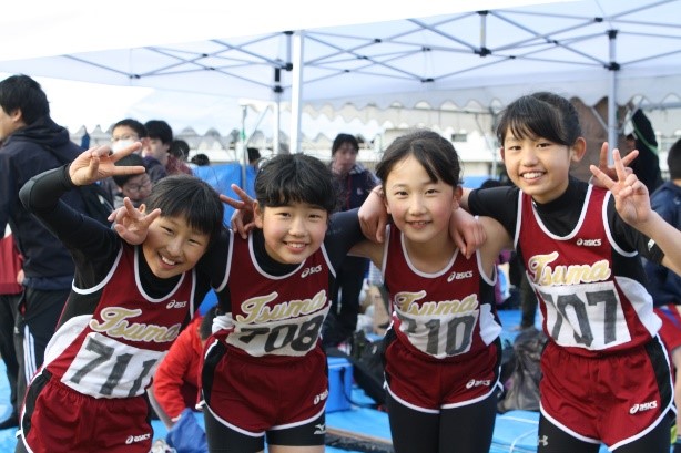 児童たちが陸上ユニフォームを着て笑顔でピースをして並んでいる写真