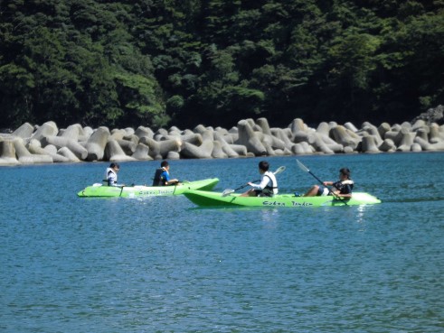 児童たちが海でカヌーをこいでいる写真