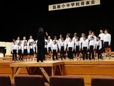 舞台で児童たちが整列し合唱している写真