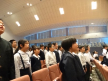 観客席で児童が立ち歌っている写真