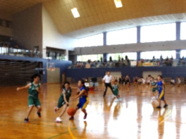 体育館で女子児童たちがバスケット試合をする写真