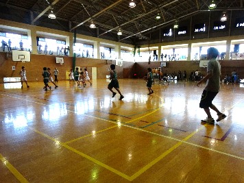 体育館で男子児童たちがバスケットボールの試合をしている写真
