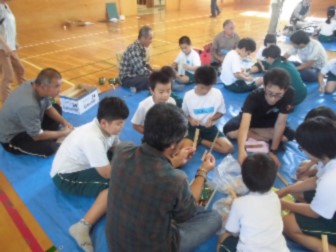 体育館で児童たちが地域の講師の方と一緒に工作している写真