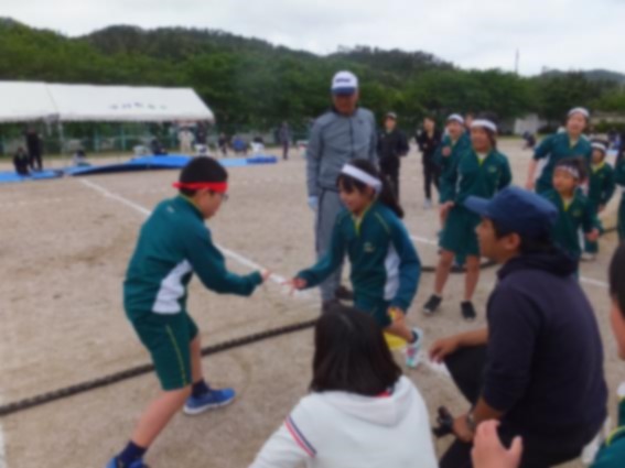 曇り空のなか小学校の校庭で赤組と白組の代表の児童がじゃんけんをしている写真