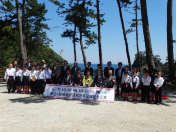 綺麗な晴天の式典に参加している生徒たちと数人の大人たちが並んで記念撮影をした写真