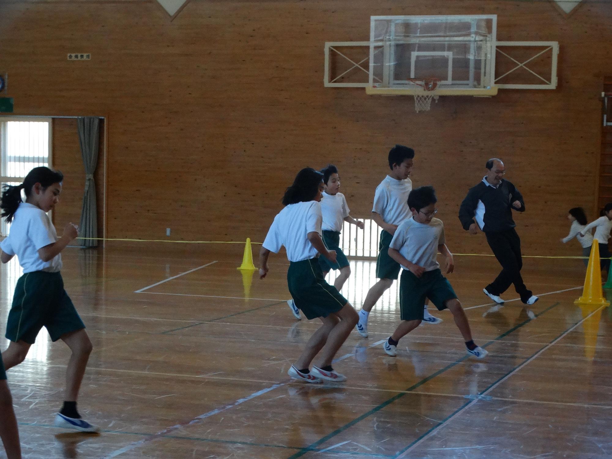 体育館で三角コーンを置き、児童たちがシャトルランをしている写真