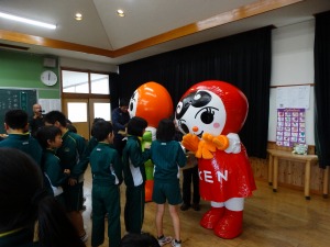 体操服姿の複数の児童が2体の着ぐるみと触れ合っている写真