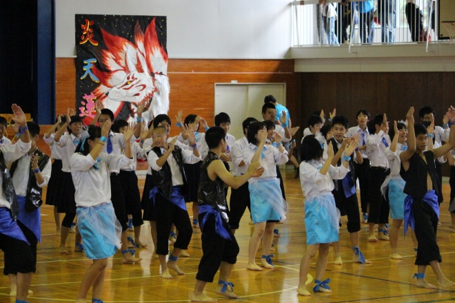 体育館で応援合戦用の衣装を着用した生徒たちが両手を広げている写真