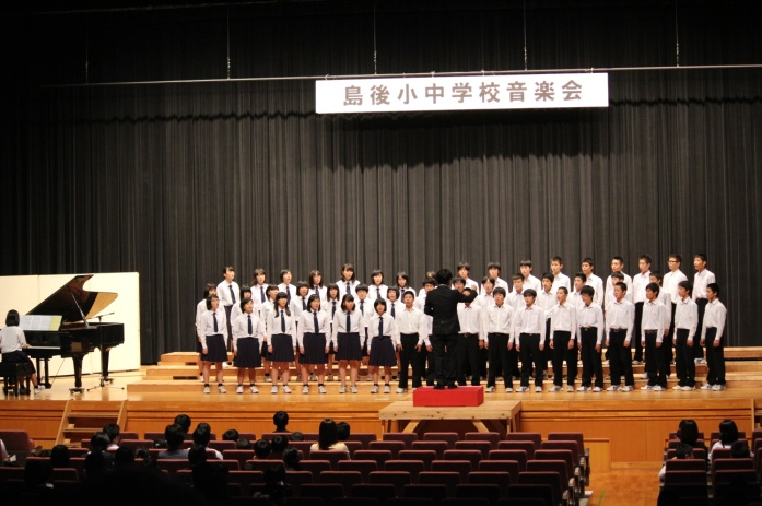 ステージ上で生徒が指揮者の方を向き合唱している写真