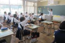 教室で生徒たちが手を挙げている写真