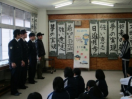 教室で制服姿の警察官が前に立ち、生徒が座って話を聞いている写真