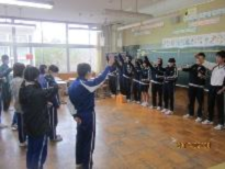 教室で生徒たちが円になり手を挙げながら活動する様子の画像