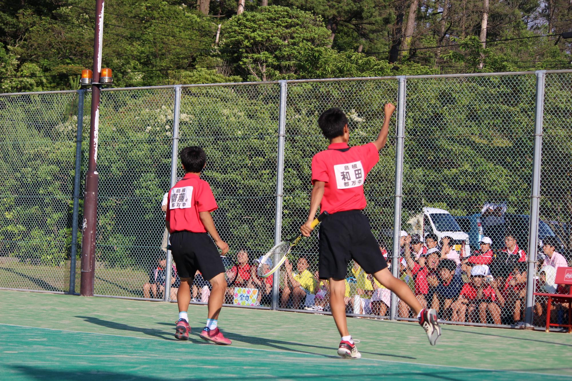 男子ダブルスの選手が右手を挙げている写真