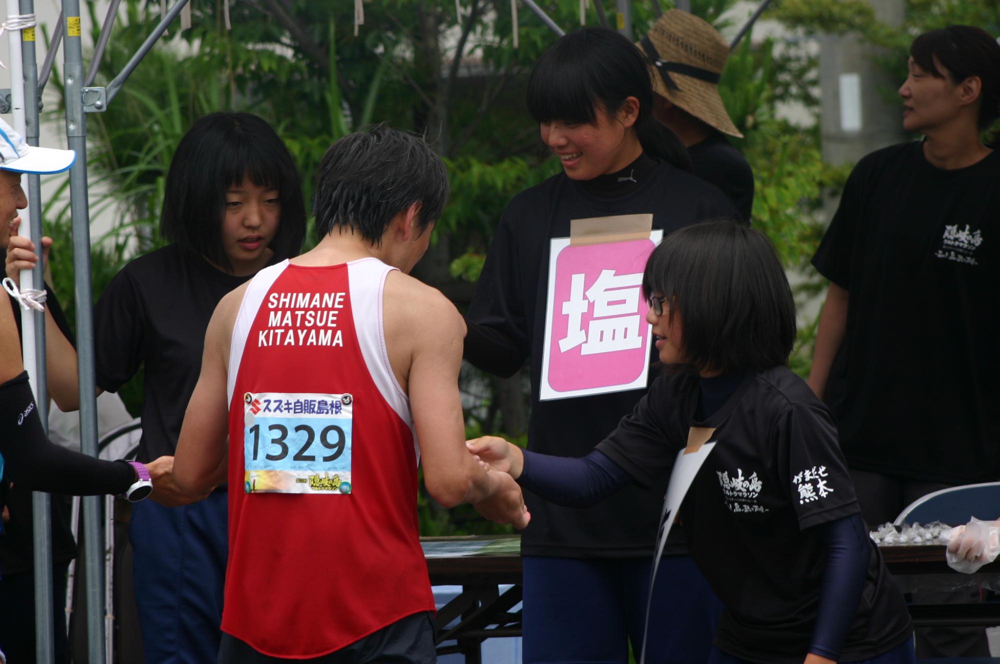 マラソン選手に塩分補給のサポートを行う生徒たちの写真