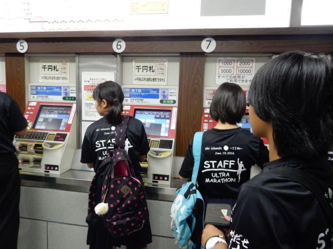 切符を購入するために券売機を操作している生徒の写真