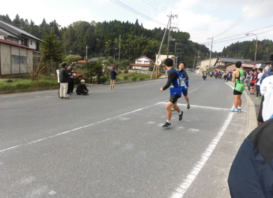 道路上でユニフォーム姿の生徒が襷を受け渡している写真
