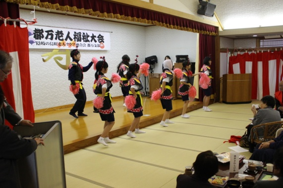 揃いの衣装に身を包んだ生徒がポンポンを手に持ち演技している写真