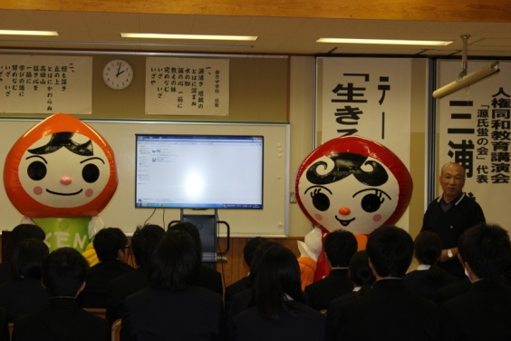 2体の着ぐるみがいる部屋で複数の生徒が前方のモニターを見ている写真