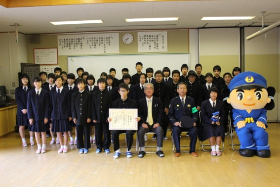 賞状を持った男子生徒や着ぐるみが前に座り、後ろに生徒が並び記念撮影をしている写真