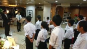 修学旅行先の宿泊先で生徒たちが先生の話を聞いている写真