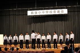 舞台で三年生生徒たちが指揮者に合わせて合唱している写真