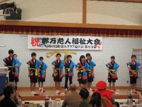 舞台で衣装を着た児童が踊りを披露し、整列して挨拶をしている写真