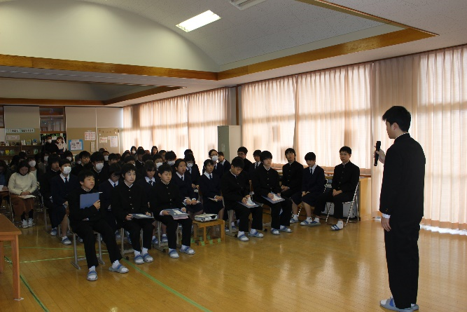 中学校の教室で一人の生徒がみんなの前に立ち自分の夢について話をしている写真