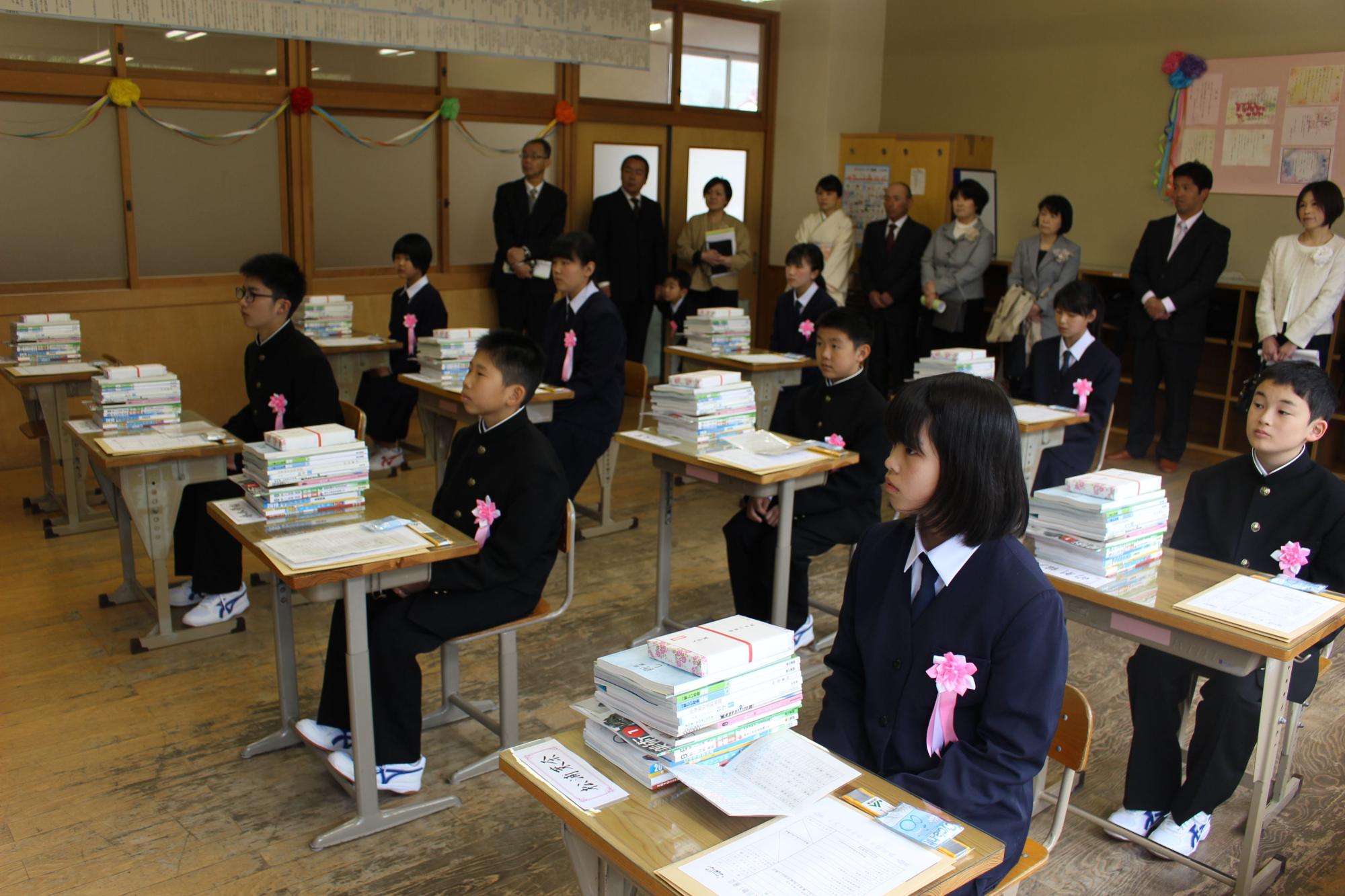 新入生が自分の椅子に座っていて机上に教科書が乗っている写真