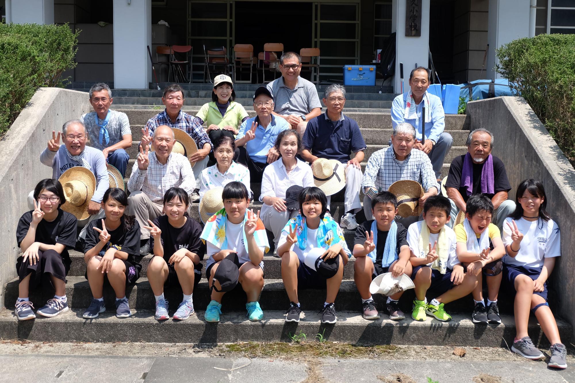 生徒たちが地域の人たちと屋外の階段で記念撮影している写真