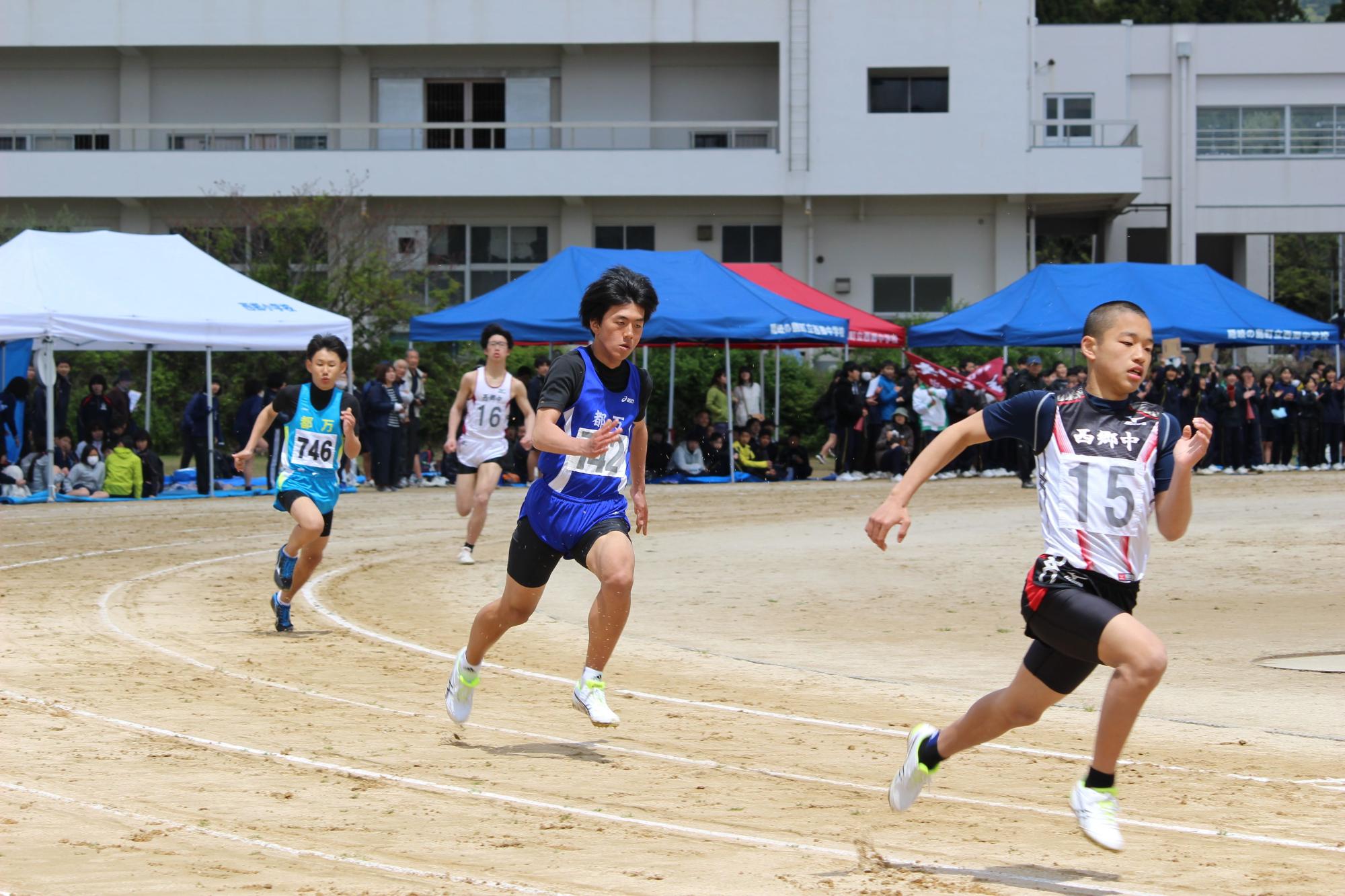 グラウンドのトラックのコーナーを生徒たちが走っている写真