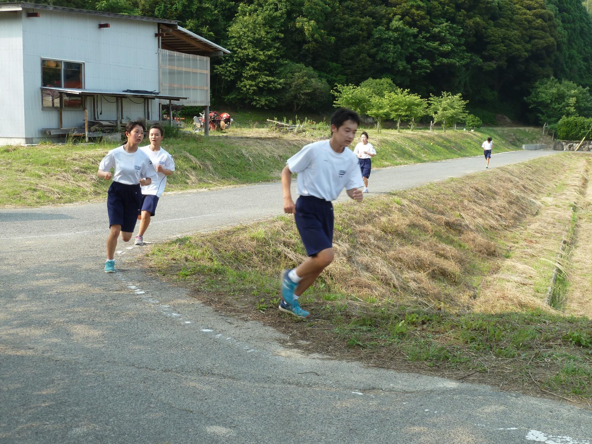 道路の曲がり角を生徒たちが走っている写真