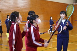 体育館で複数の生徒がラケットを持ち練習している写真