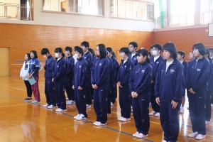 体育館で複数の生徒が整列して前を向いている写真