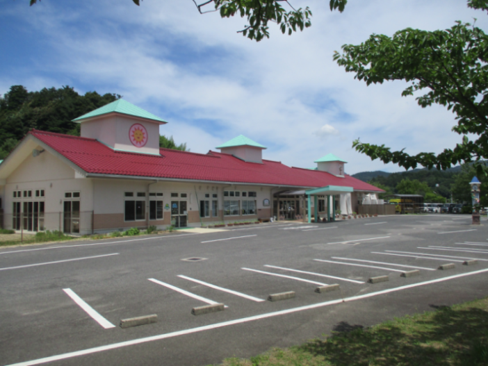 赤い三角屋根の建物の手前に駐車場がある写真