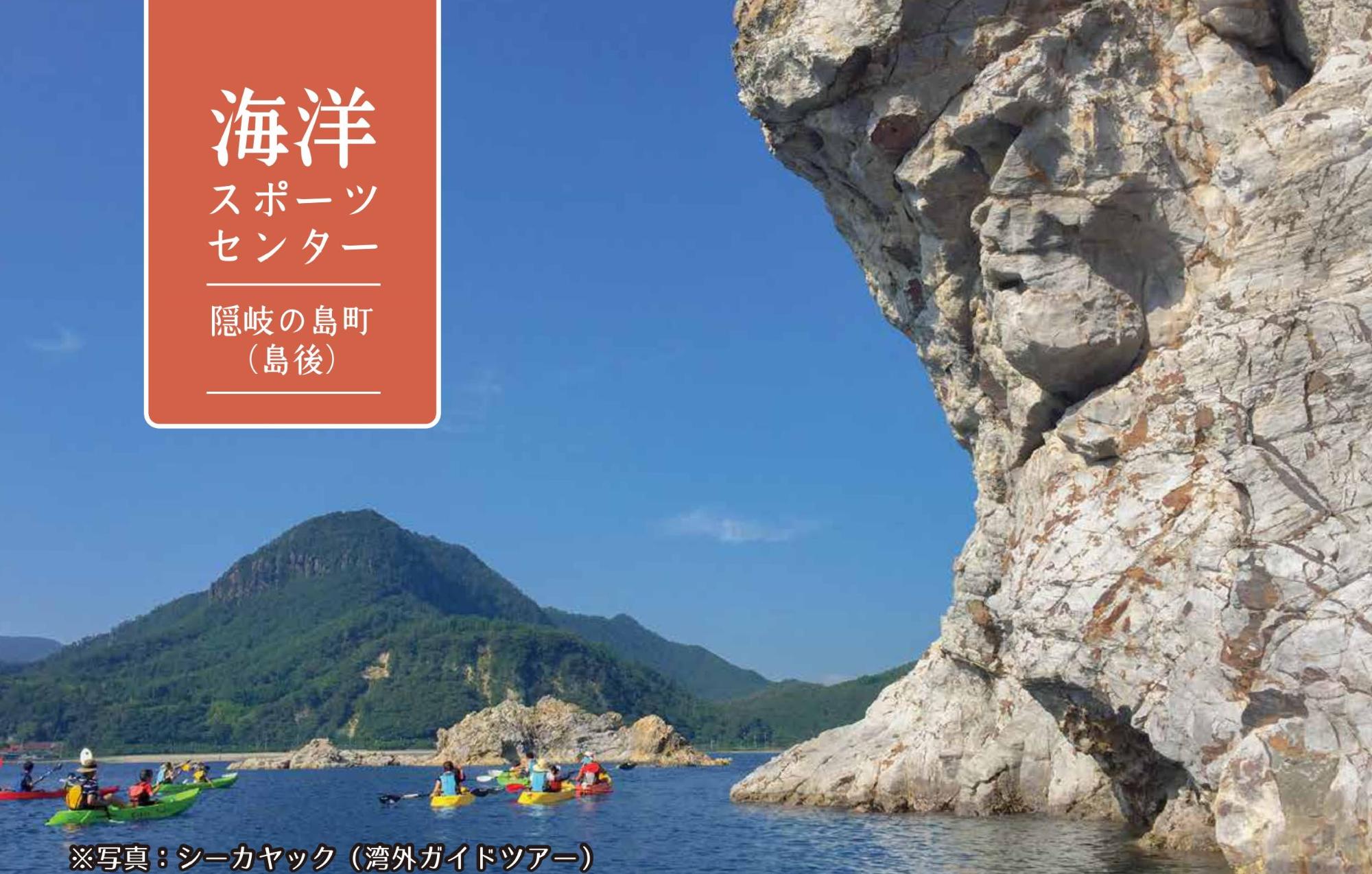 巨大な岩場の下で人々がシーカヤックを楽しんでいる海洋スポーツセンターの写真