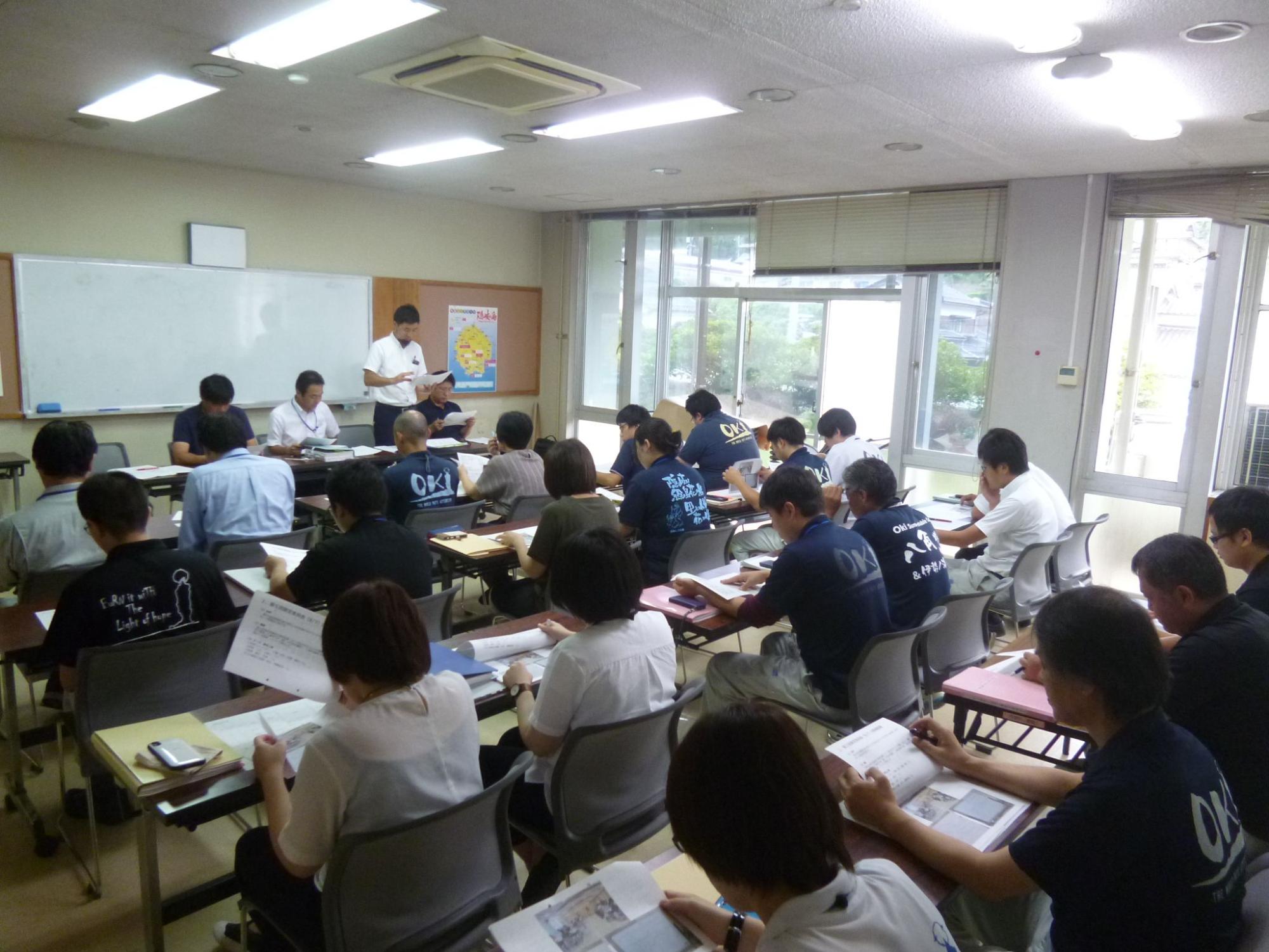 委員会の進行役の人とそれを聞いている職員たちの写真