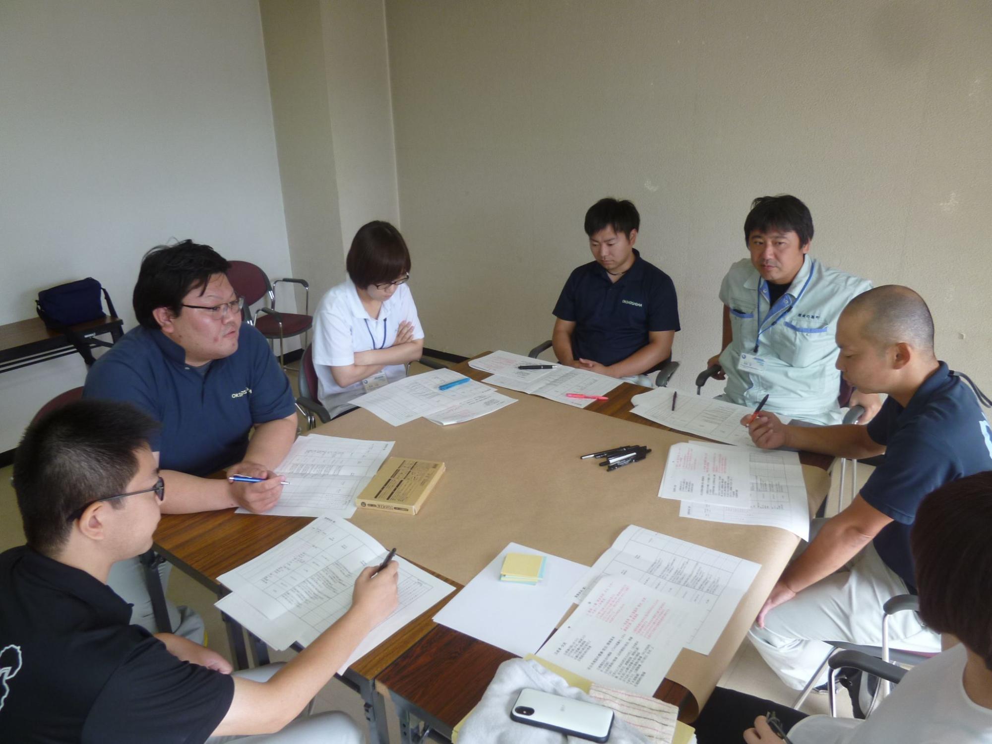 男性5人と女性2人のグループで話し合いをしている職員たちの写真