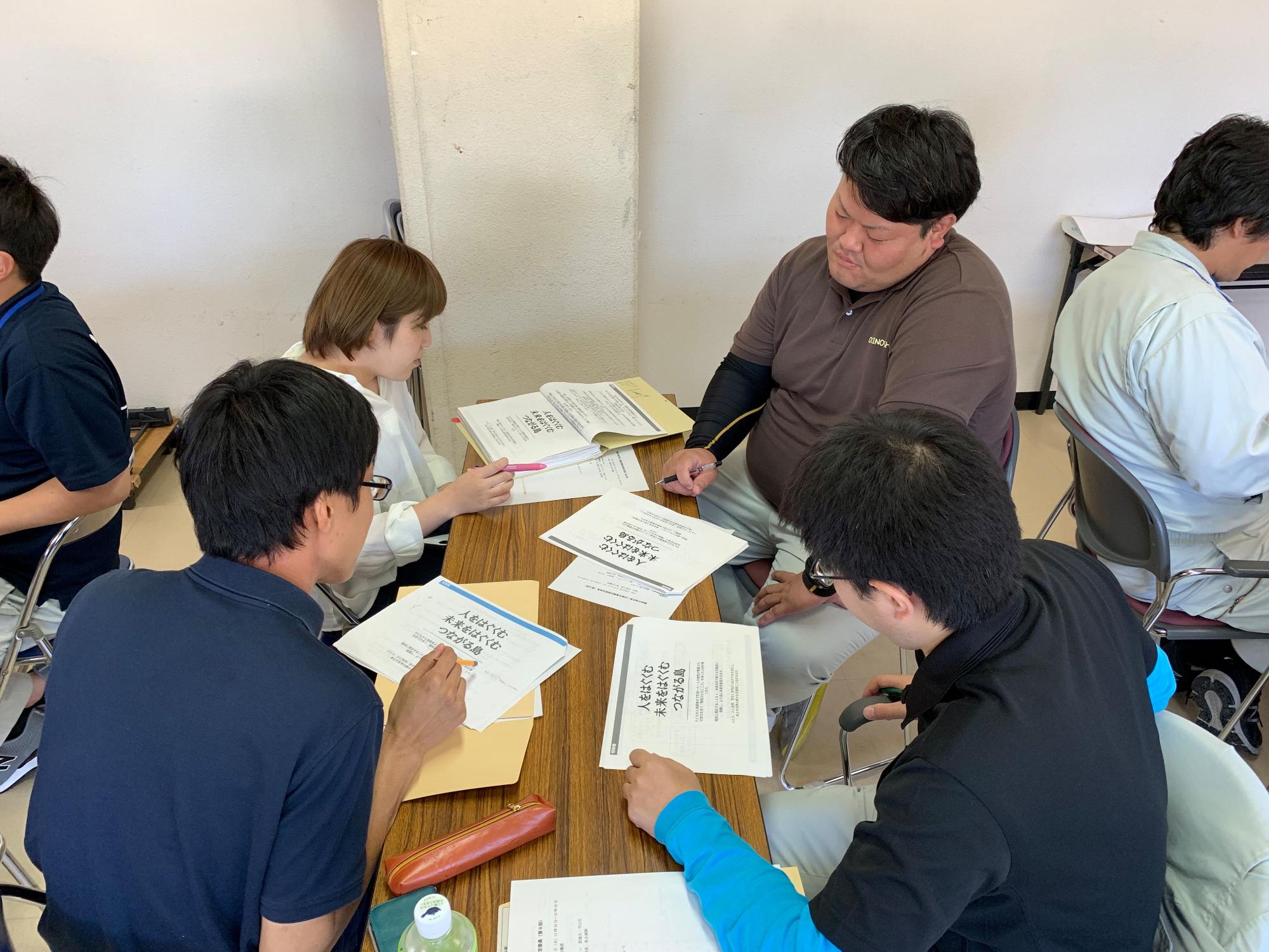 男性3人と女性1人のグループで話し合いをしている職員たちの写真